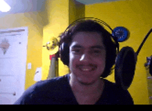 a man wearing headphones and a black shirt smiles for the camera