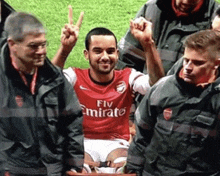 a soccer player wearing a fly emirates jersey holds up his fist