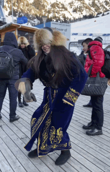 a woman in a blue and gold dress is dancing in front of a sign that says " tower of "