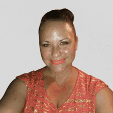 a woman wearing a pink top and gold necklace smiles for the camera