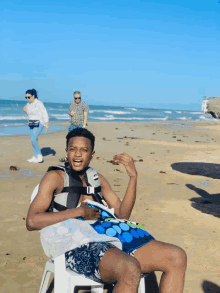 a man wearing a life jacket is sitting on a beach