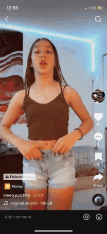 a girl in a brown tank top and blue shorts is on a tiktok video