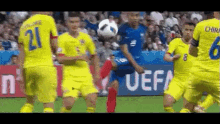 a group of soccer players are playing a game on a field with a uefa sign in the background .