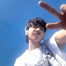 a young man wearing headphones and a shirt that says ' new york ' on it is giving a peace sign