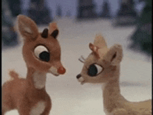 two stuffed deer are standing next to each other in the snow .