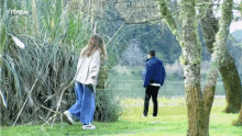 a man and a woman are walking in a park with the letters rtve on the bottom of the screen