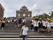 a woman stands on a set of stairs in front of a building with a crowd of people