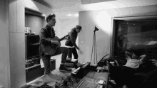 a black and white photo of a man playing a guitar in a room with a sign on the wall that says " hdr "