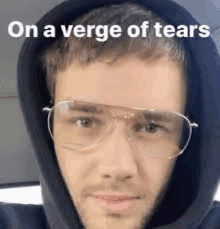 a man wearing glasses and a hoodie with the words `` on a verge of tears '' .