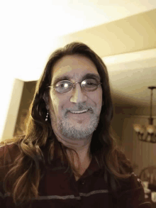 a man with long hair and glasses smiles for a picture