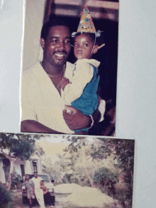 a man is holding a child with a birthday hat on