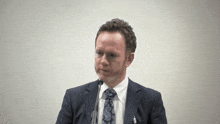 a man in a suit and tie stands at a podium