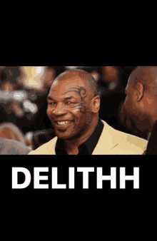 a man with a tattoo on his forehead is smiling in front of a sign that says delithh