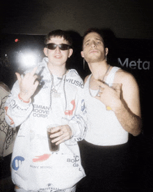 two men standing next to each other with one wearing a hoodie that says sony music on it