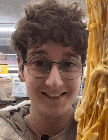 a young man wearing glasses is smiling in front of a sign that says lg