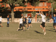 a group of people are playing frisbee in front of a wall that says ' pal ng ' on it