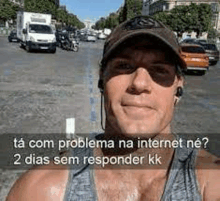 a man wearing a hat and sunglasses is taking a selfie in front of a street .