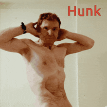 a naked man stands in front of a wall with the word hunk on it