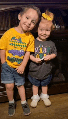 a boy and a girl are posing for a picture and the boy is wearing a mardi gras shirt