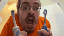 a man wearing glasses is holding two electric toothbrushes