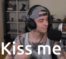 a man wearing headphones stands in front of a microphone with the words kiss me behind him