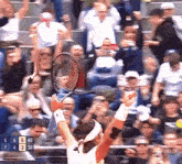 a tennis player holds up his racket in front of a crowd with a scoreboard that says 5 6 5 40 7 4 30