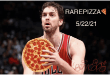 a basketball player is holding a pepperoni pizza in his hands