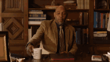 a man sitting at a desk drinking from a mug that says " i 'm a scientist " on it