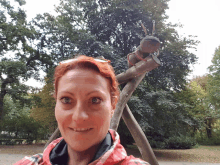 a woman in a red jacket smiles in front of a tree sculpture