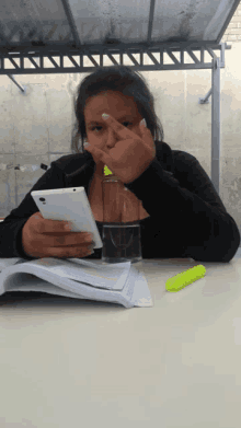 a woman sitting at a table holding a cell phone