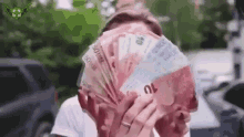 a man is covering his face with a fan of money .