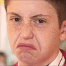 a close up of a young boy 's face with freckles making a funny face .