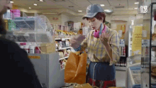 a woman wearing headphones and a ny hat is standing in front of a cash register in a store .