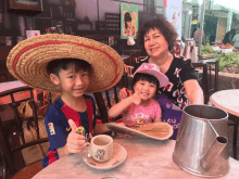 a girl wearing a shirt that says let 's is sitting at a table with two children