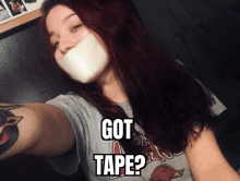 a woman is taking a selfie with tape on her mouth .