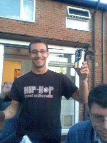 a man wearing a shirt that says hip hop is holding a can of beer