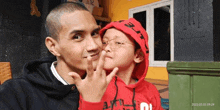 a man and a little girl are posing for a picture together . the little girl is wearing a red hoodie .