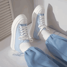 a pair of light blue sneakers with white laces on a person 's feet