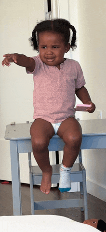 a little girl wearing a diaper sits on a table