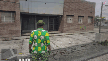 a man in a green and yellow floral shirt stands in front of a brick building in a video game