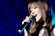 a woman singing into a microphone with a blue background