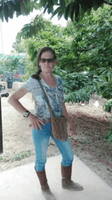 a woman standing in front of a tree wearing sunglasses and a watch