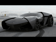 a black lamborghini supercar is parked on the side of a road .