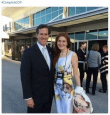 a man in a suit and tie is posing for a picture with a woman in a floral dress .