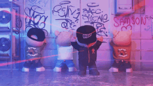 a group of teddy bears standing in front of a wall with graffiti on it