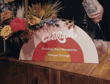 a sign that says cocktails on it is on a wooden table