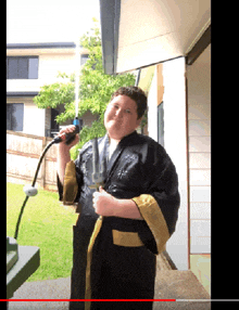 a boy in a black robe is holding a hose