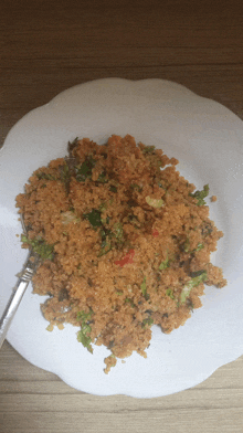 a white plate topped with rice and vegetables with a fork on it