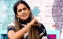 a woman is sitting in front of a brick wall and holding her hair in her hand .