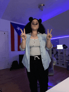 a woman giving a peace sign in front of a flag